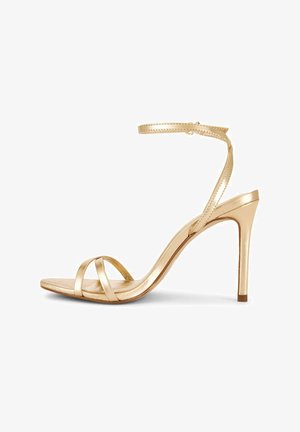 Sandalo alto in metallo dorato con sottile cinturino alla caviglia e due cinturini anteriori, tacco a stiletto e punta aperta.