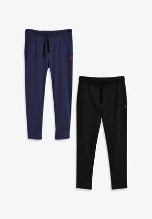 Due paia di pantaloni della tuta con taglio conico e coulisse, uno blu navy con logo rosso, uno nero con logo blu, distesi su uno sfondo bianco.