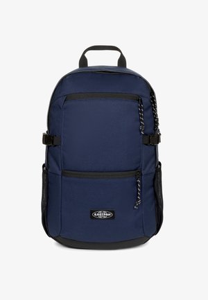 Mochila azul marino de tela resistente; cuenta con dos bolsillos frontales con cremallera, asa superior y correas ajustables. Fondo negro y bolsillo lateral de malla.