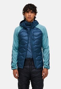 Gevoerde jas met een capuchon, voorzien van een marineblauwe gewatteerde voorkant en teal mouwen. Soepele stof, ritszakken en een getailleerd ontwerp.