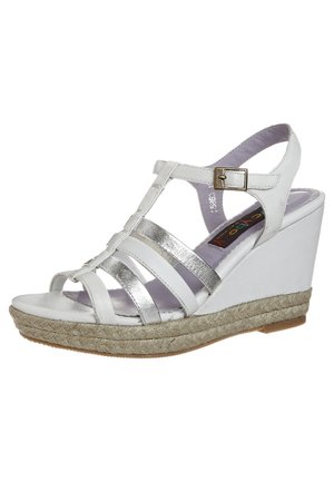 Hvide kilehæle med krydsede metalliske sølvremme, en justerbar spænde og en tekstureret espadrille-stil platform.