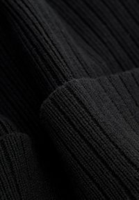 Tessuto nero lavorato a maglia con trama a coste verticali, che mostra una superficie morbida e pelosa e un colore intenso. Adatto per capi di abbigliamento caldi.