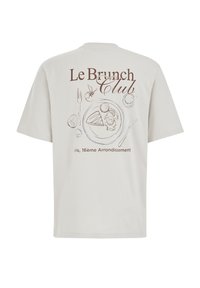 Gaišs pelēks kokvilnas t-krekls ar īsām piedurknēm, ar brūnu kontūru grafiku, kas attēlo brokastu šķīvi, un uzrakstu "Le Brunch Club" aizmugurē.