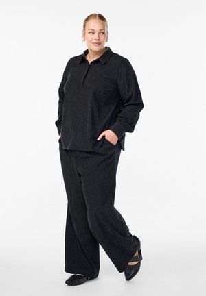 Ensemble deux pièces en tissu noir et doux, comprenant une chemise à col à manches longues et un pantalon à jambes larges. Les détails notables incluent des poches latérales.