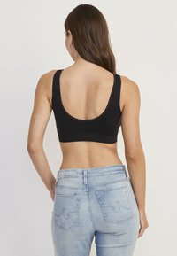 Sort crop top med rund halsudskæring, brede stropper og en glat tekstur, parret med lyseblå jeans med højt talje og baglommer.