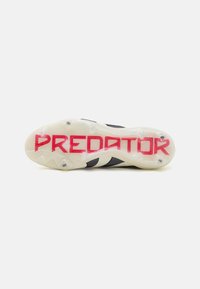 Predator soccer cleat with a black and white design, featuring a translucent outsole and bold red “PREDATOR” text on the sole.