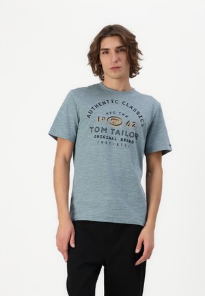 Hellblaues Kurzarm-T-Shirt mit Rundhalsausschnitt, versehen mit einem bedruckten Logo in Schwarz und Gold, aus einem weichen Textil gefertigt.