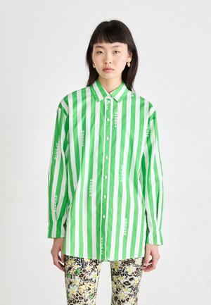 Green and white striped shirt with button closure, long sleeves, featuring text print. Paired with patterned floral and animal print leggings.