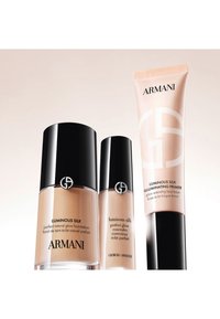 Trois produits de maquillage Giorgio Armani Luminous Silk : fond de teint, correcteur et base illuminateur avec des caps noirs sur un fond clair.