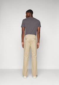 Beige broeken met een rechte pijpdesign, weergegeven met een charcoalgrijze t-shirt, die een eenvoudige, gladde textuur laat zien.