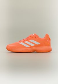 Φωτεινό πορτοκαλί αθλητικό παπούτσι με λευκό σχέδιο τριών ρίγων, υφασμένο πέλμα και κορδόνια σε ουδέτερο γκρι φόντο.