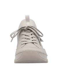 Basket beige avec un tissu texturé et des accents lisses, présentant un bout rond, des lacets plats beiges et une bride à l'arrière.