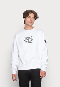 Witte sweatshirt van katoen, met een zwart grafisch logo op de borst, ribbelmanchetten en onderrand. Eenvoudig ontwerp zonder aanvullende patronen.
