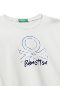 Witte T-shirt met ronde hals, voorzien van een vervaagd blauw abstract logo en "Benetton" in zwarte schrift op de voorkant.