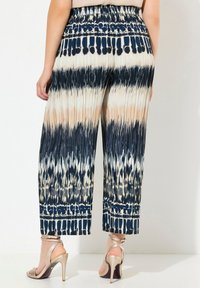 Breda byxor med veck i en marinblå, beige och krämfärgad tie-dye mönstring med en texturerad yta och resårmidja.