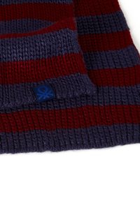 Gebreide sjaal in donkerblauw en rode strepen. Ribbelstructuur met een klein blauw label met een logo aan de rand. Zachte stof.