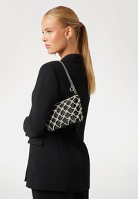 Borsa nera con tracolla in catena metallica argentata, caratterizzata da un design intrecciato a forma di diamante. Texture liscia con accenti scintillanti.