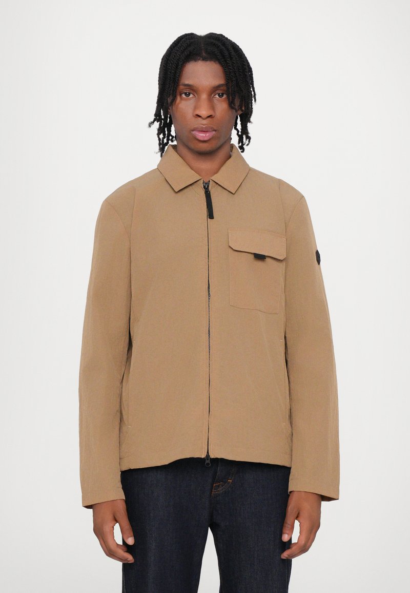 Braune leichte Jacke mit Kragen, Frontreißverschluss und einer Brusttasche. Verfügt über lange Ärmel und eine glatte, strukturierte Oberfläche.