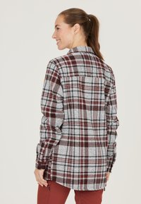 Punainen ja harmaa ruudullinen flanellipaita pitkillä hihoilla, napitettuina cuffeina ja kaarevalla helmalla. Sisältää takahalkion ja pehmeän tekstuurin.