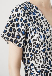 Abito a maniche corte in tessuto leggero e liscio con stampa leopardata blu e nera su sfondo bianco, dotato di scollatura a V e vita aderente.