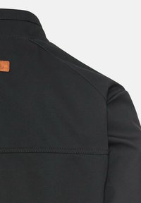 Sort skjorte med et struktureret stof. Har en brun læderlap på ryggen. Glat, semi-pasformet design med en klassisk krave.