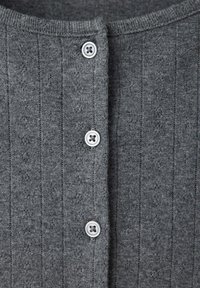 Tissu tricot gris avec un motif côtelé vertical et trois boutons blancs cousus en ligne centrale.