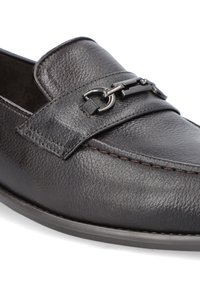Czarne skórzane mokasyny o teksturowanym wykończeniu, z szerokim paskiem i dekoracyjnym łańcuszkiem z przodu. Widoczne szwy.
