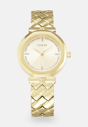 Zlaté hodinky s okrúhlym ciferníkom, textúrovaným vrkočovým remienkom a svetlým zlatým ciferníkom s diamantovými akcentmi a striebornými hodinovými ukazovateľmi.