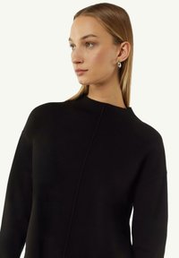 Black knitted sweater with a high neck, dropped shoulders, and ribbed cuff detailing; features a clean, minimalistic design without embellishments.