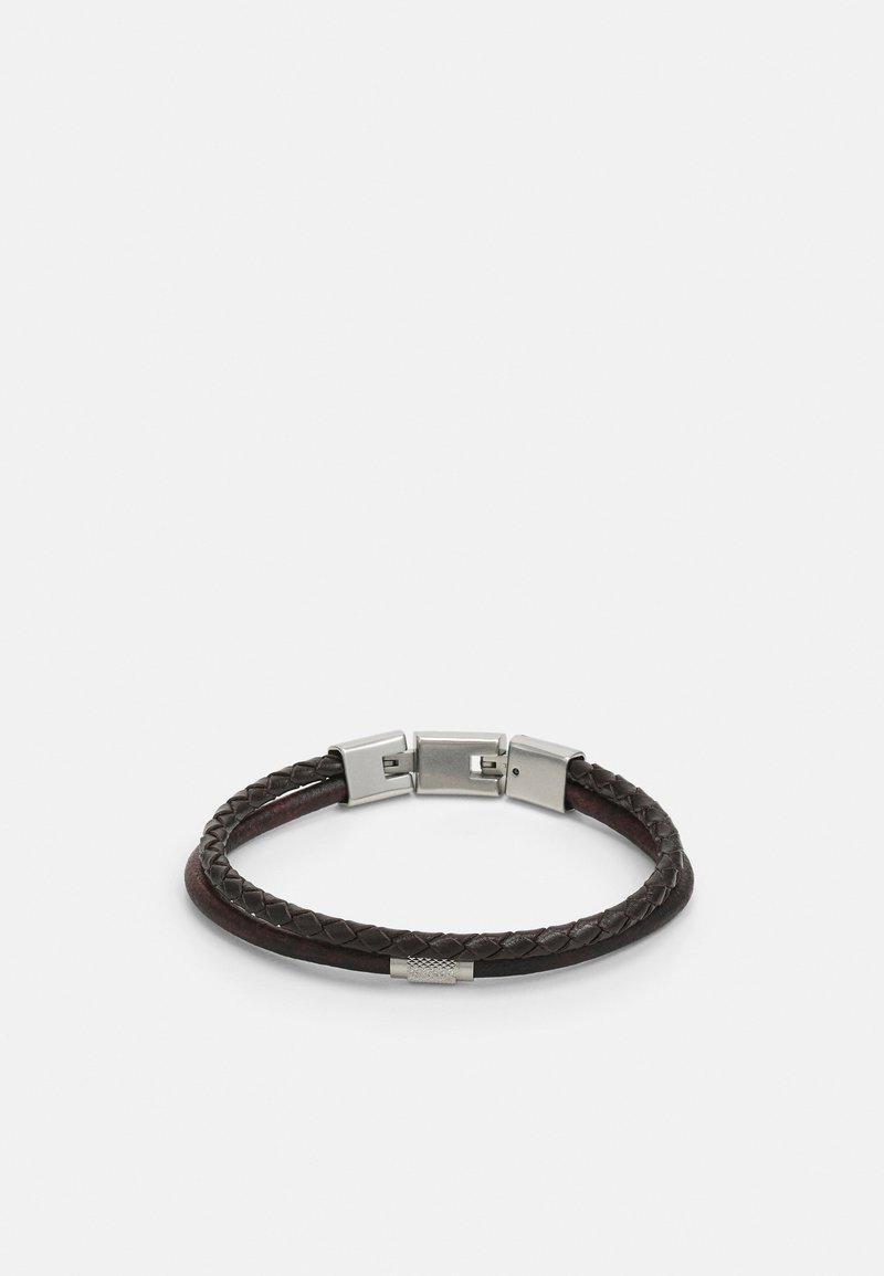 Brun flätad läderarmband med spänne i silverfärgad metall. Har en texturerad cylindrisk detalj och en slät yta.