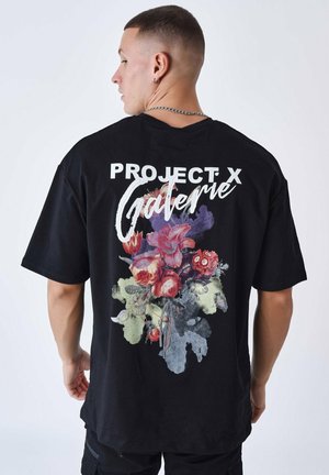 Zwarte katoenen T-shirt met een grote bloemenafbeelding in kleuren zoals rood, paars en groen, met de tekst "PROJECT X" en "Galerie" in het wit.