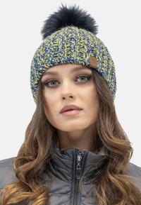 Beanie lavorato a maglia caratterizzato da un design blu e giallo, decorato con un pompon nero. Include un motivo testurizzato e un'etichetta in pelle.