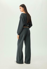 Donkergrijs cropped sweatshirt met pofmouwen en bijpassende wijde broek. Zachte stof met een gladde textuur en elastische tailleband.