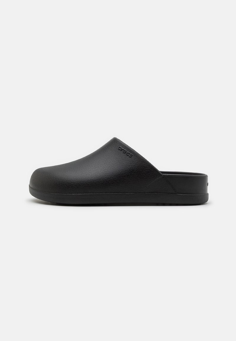 Sabot noir à enfiler avec bout fermé et surface texturée, doté d’un talon bas et d’un logo discret près de l’ouverture.