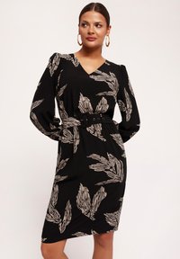 Czarna sukienka z dekoltem w szpic, długimi rękawami i �ściągniętą w talii paskiem. Na materiale ornament w postaci beżowych liści.