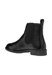 Botas de cuero negras hasta el tobillo con paneles laterales elásticos, punta redondeada, detalles decorativos de brogue y un tacón bajo y apilado.