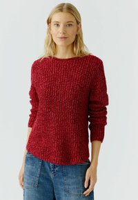 Roter gestrickter Pullover mit strukturiertem Muster, rundem Ausschnitt und langen Ärmeln. Kombiniert mit Jeans, die einen lässigen Stil zeigen.