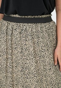 Krila s leopardjim vzorcem, izdelana iz lahko tkanine z bež osnovo, z črnimi pikami, elastičnim pasom in nabranimi teksturami.