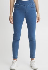 Jeggings de denim azul con cintura elástica, bolsillos laterales y un fit ajustado. La tela tiene una textura suave y es ligeramente elástica.