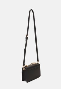 Borsa a tracolla in pelle nera con un accento in chain oro e una tracolla regolabile. Presenta una forma rettangolare slanciata e una chiusura a patta.