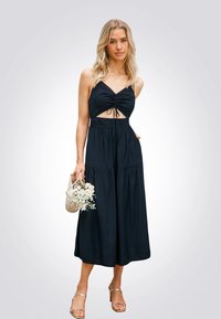 Zwart maxi-jurk met spaghetti-strepen, uitsnijding aan de voorkant, geraffineerde bodice en gelaagde zoom. Gecombineerd met eengeweven tas van bloemen.