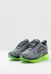 Grå sportskor med strukturerad ovandel, svarta accenter och neongrön sula. Har snörningssystem och vadderad krage för komfort.