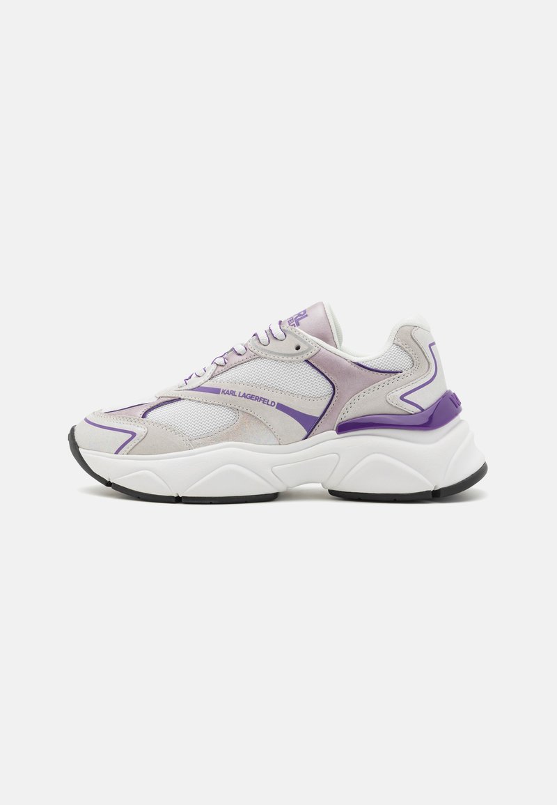 Zapatilla deportiva blanca y morado claro con paneles de malla y ante, suela gruesa blanca y la marca "KARL LAGERFELD" en el lateral y la lengüeta.