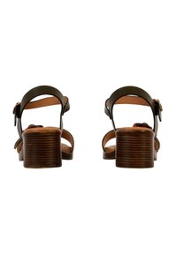Bruine heeled sandalen hebben een donkergroen leren bovenwerk en verstelbare enkelbandjes. De blokhak heeft een geribbeld oppervlak voor extra grip.