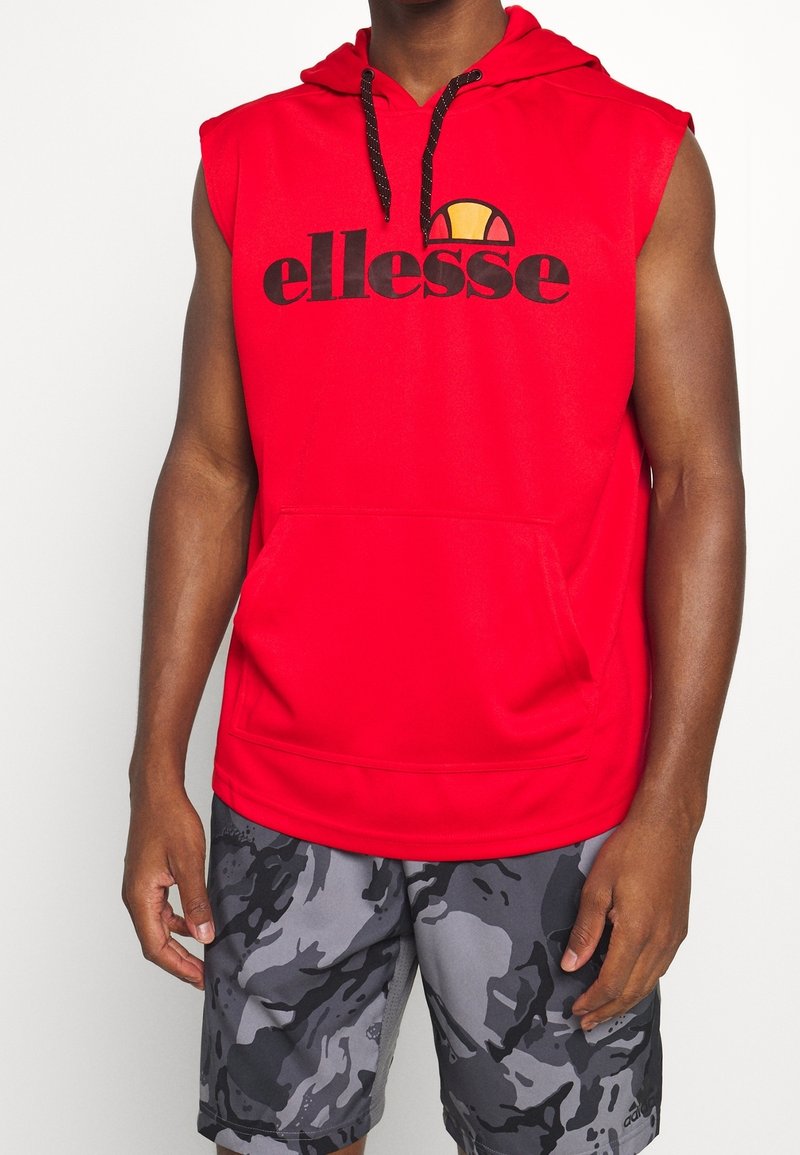 Red sleeveless hoodie with black "ellesse" logo and round graphic. Features a front pocket and adjustable black drawstring on the hood.