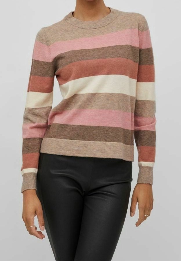 Femme portant un pull à manches longues avec col rond et rayures horizontales rose, marron, crème et rouille, associé à un pantalon en cuir noir.