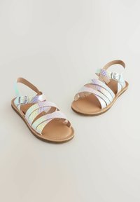 Sandali intrecciati iridescenti con più cinghie incrociate, fibbia regolabile e suola piatta. Interno beige e suola in gomma texturizzata.