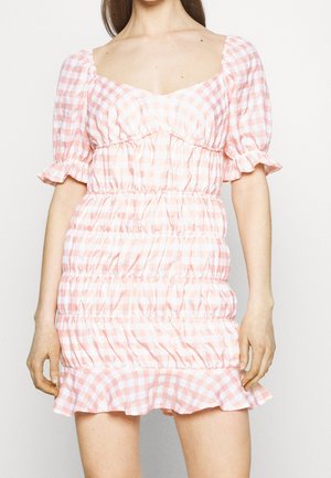 Robe à carreaux rose et blanc avec des manches bouffantes, décolleté carré, buste smocké et ourlet volanté, fabriquée en tissu léger.