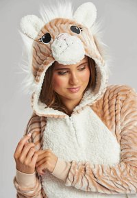 Pijama con cremallera en tejido de felpa naranja y blanca, que presenta un diseño de tigre con capucha, orejas y detalles de pelo sintético. Puños acanalados.