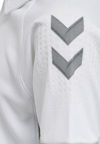 Witte sportieve shirt met textuurstof en meshpatroon. Features grijze chevronaccenten op de schouder en een ronde kraag.
